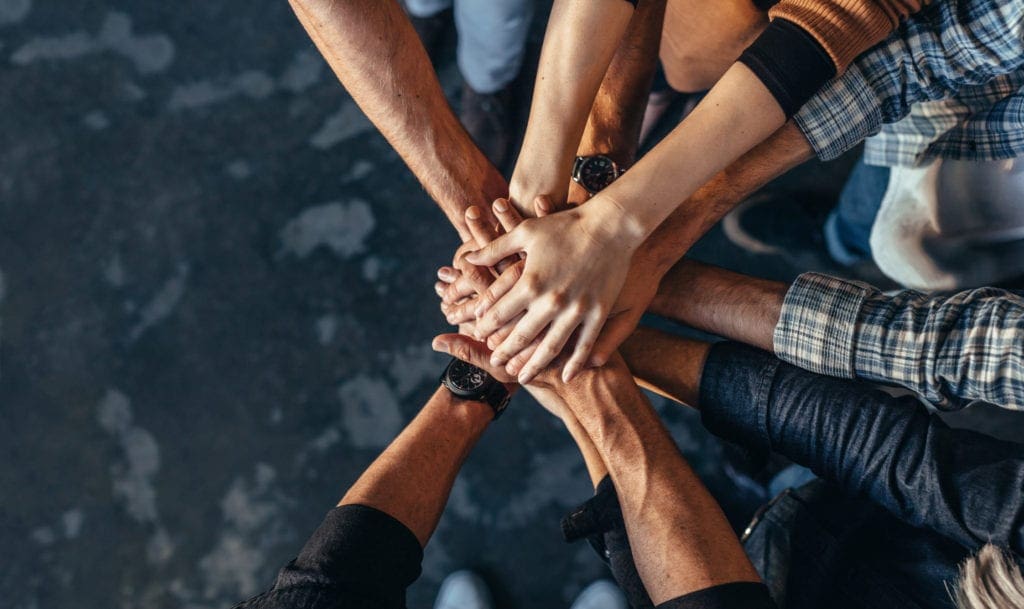 Symbol of teamwork, cooperation and unity Top view of creative professionals putting their hands together as a symbol of teamwork, cooperation and unity. Stack of hands of men and woman.