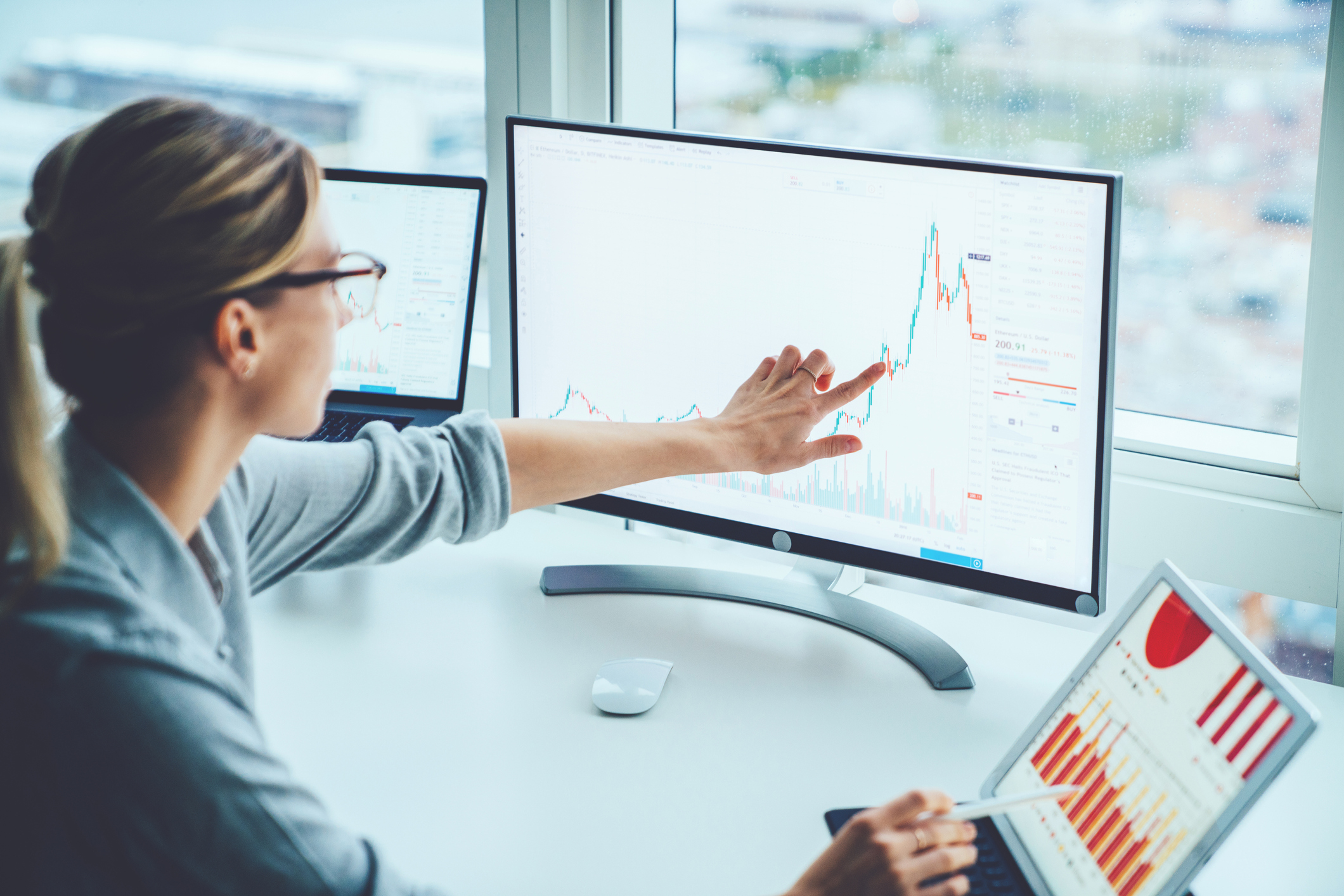 Business woman study financial market to calculate possible risks and profits.Female economist accounting money with statistics graphs pointing on screen of computer at desktop. Quotations on exchange ap Analytics
